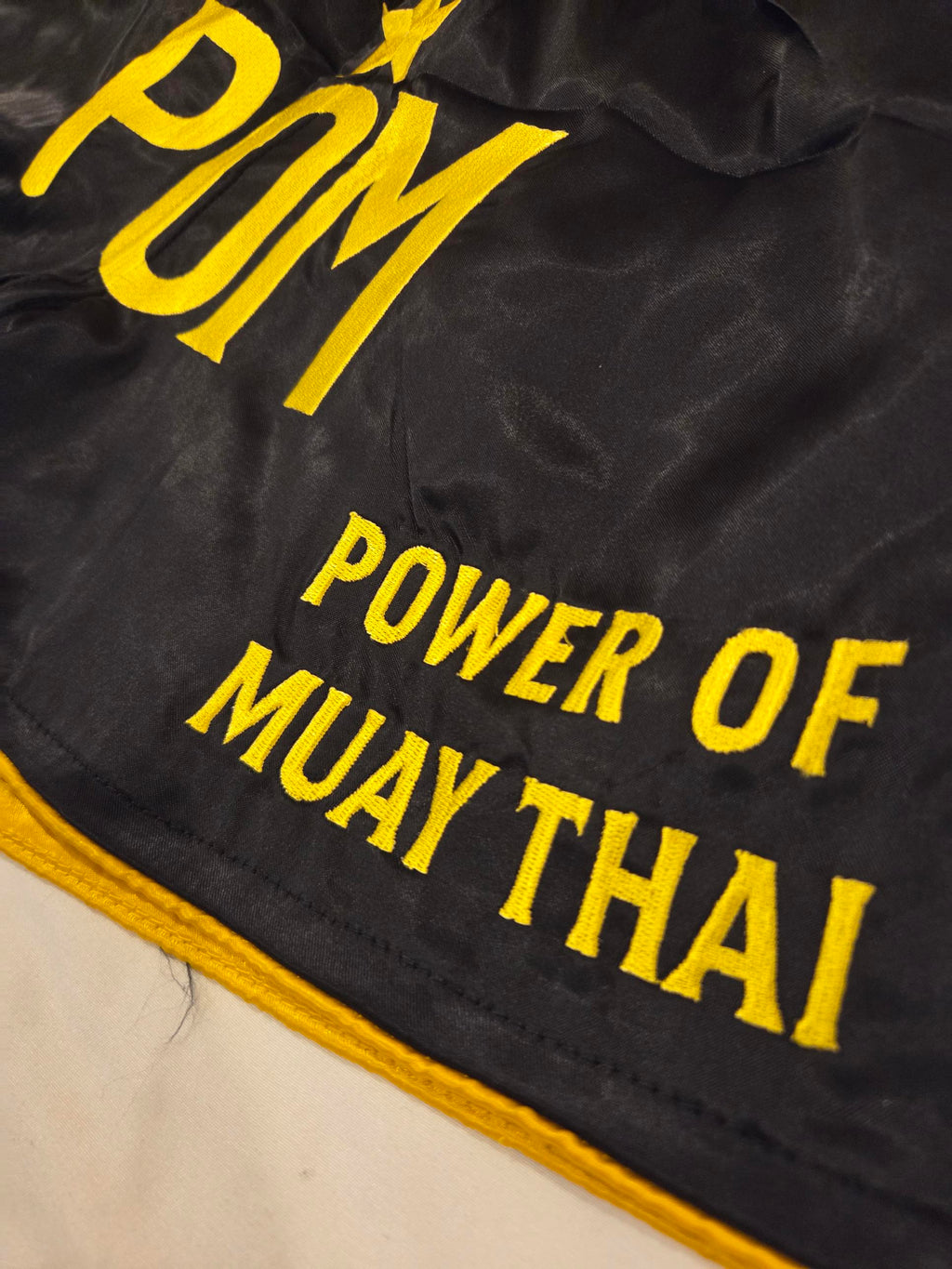 Detail: gestickter Schriftzug Power of Muay Thai am Bein